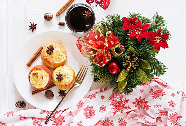 Manzanas rellenas al horno con queso cottage, pasas y almendras para Navidad en una mesa blanca. Postre de comida de Navidad.