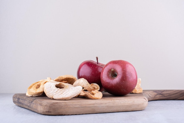 Foto gratuita manzanas y rodajas de manzana seca en una placa sobre superficie blanca