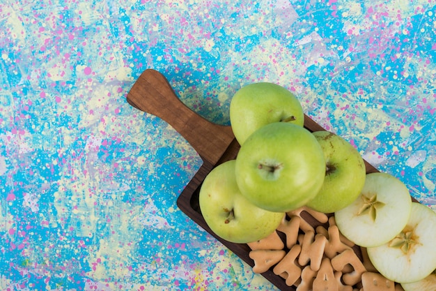 Foto gratuita manzanas en rodajas verdes con galletas en la tabla de madera en azul.