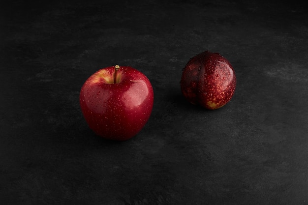 Manzanas rojas aisladas sobre fondo negro en el centro.