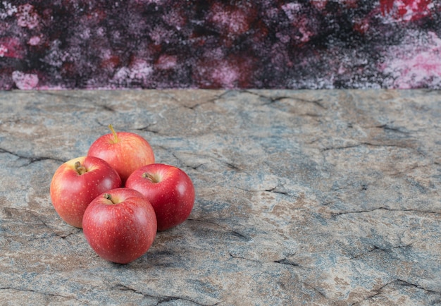 Foto gratuita manzanas rojas aisladas sobre una superficie de hormigón