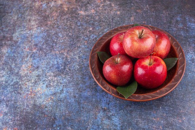 Manzanas rojas brillantes con hojas verdes sobre fondo de piedra.