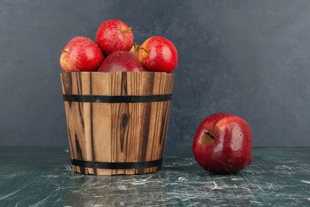 Manzanas rojas cayendo del balde sobre la mesa de mármol.