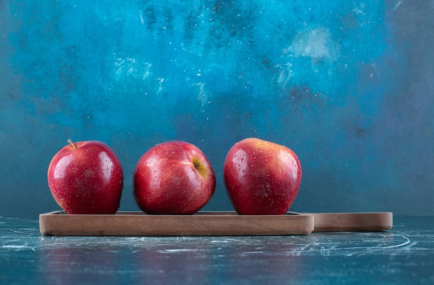 Manzanas rojas enteras sobre tabla de madera.