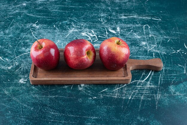 Manzanas rojas enteras sobre tabla de madera.