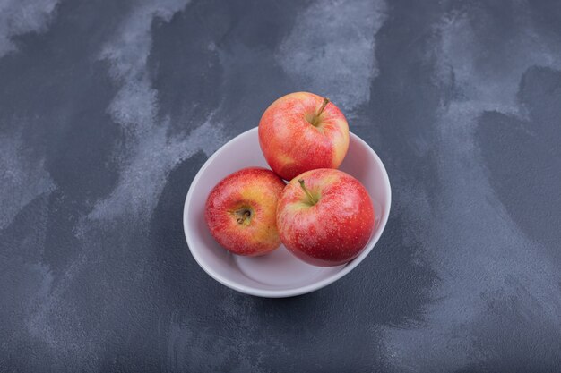Manzanas rojas frescas en un tazón blanco.