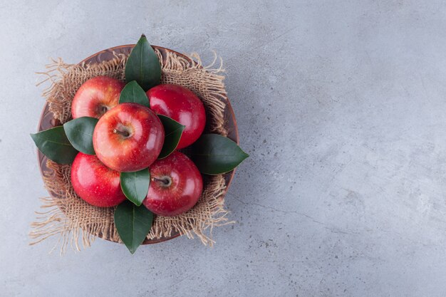 Manzanas rojas maduras colocadas sobre una mesa de piedra.