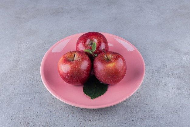 Foto gratuita manzanas rojas maduras colocadas sobre una mesa de piedra.