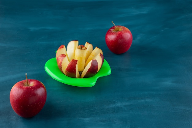 Foto gratuita manzanas rojas en rodajas frescas colocadas sobre una superficie azul.