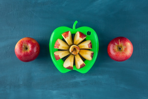 Manzanas rojas en rodajas frescas colocadas sobre una superficie azul.