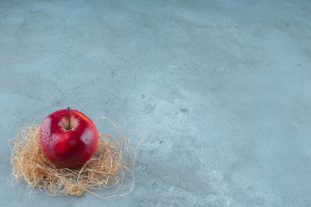 Manzanas rojas sobre paja seca, sobre el fondo de mármol. Foto de alta calidad