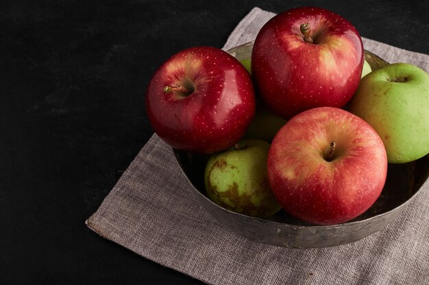 Manzanas rojas y verdes en un recipiente metálico, vista superior.