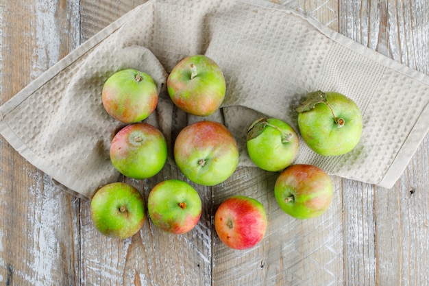 Manzanas sobre madera y toalla de cocina.