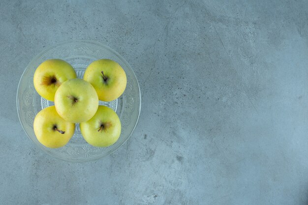 Manzanas sobre un pedestal de vidrio, sobre el fondo de mármol. Foto de alta calidad