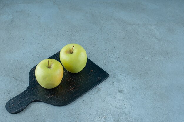 Manzanas en una tabla para cortar, sobre el fondo de mármol. Foto de alta calidad