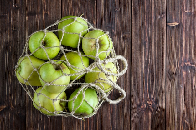 Foto gratuita manzanas verdes en una bolsa de red vista superior sobre un fondo de madera espacio libre para su texto