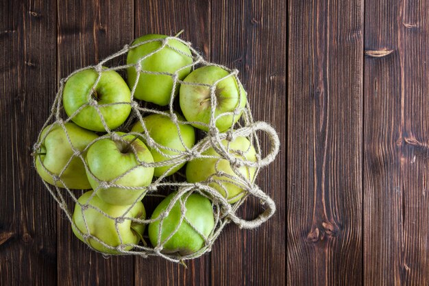 Manzanas verdes en una bolsa de red vista superior sobre un fondo de madera espacio libre para su texto