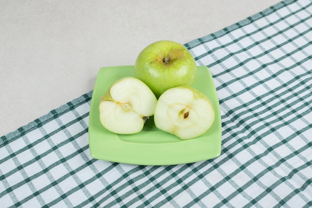 Foto gratuita manzanas verdes cortadas a la mitad en placa verde