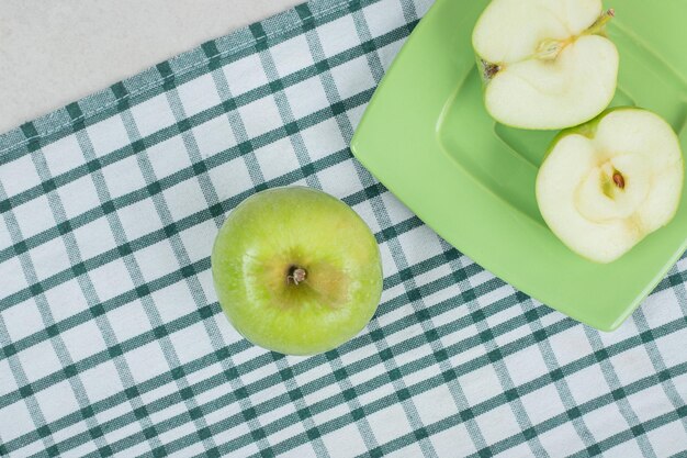 Manzanas verdes cortadas a la mitad en placa verde