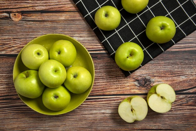 Manzanas verdes en un cuenco de cerámica verde sobre una toalla marcada