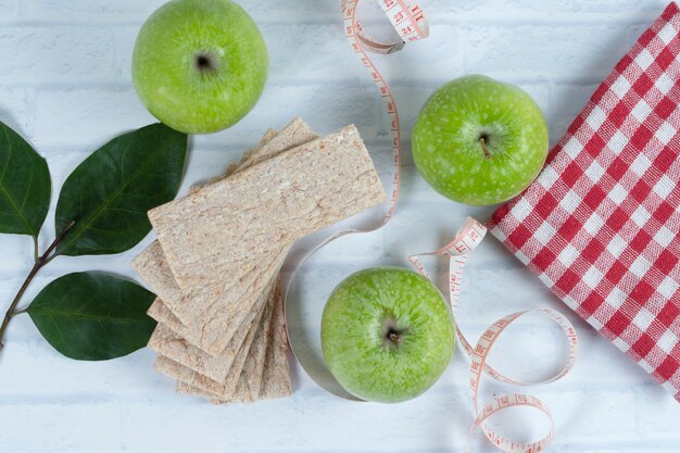 Manzanas verdes enteras con cinta métrica y pan saludable crujiente.
