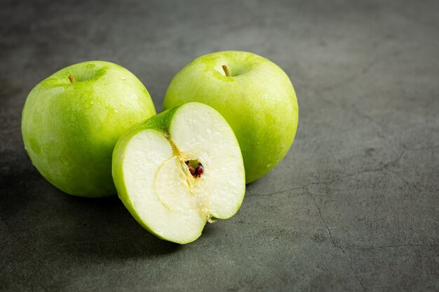 Manzanas verdes frescas cortadas por la mitad poner sobre fondo oscuro
