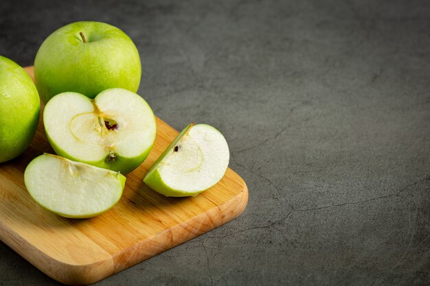 Manzanas verdes frescas cortadas por la mitad puestas sobre tabla de cortar de madera