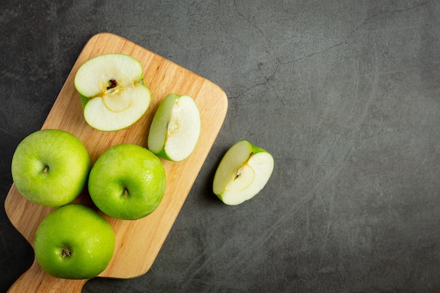 Manzanas verdes frescas cortadas por la mitad puestas sobre tabla de cortar de madera