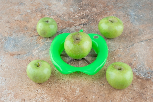 Manzanas verdes frescas con peladora de mesa de mármol.