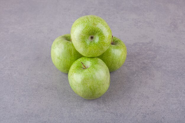 Manzanas verdes maduras frescas colocadas sobre una superficie de piedra.