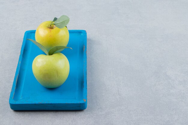 Manzanas verdes maduras en placa azul.