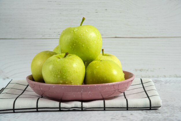 Manzanas verdes en un platillo de cerámica sobre la toalla