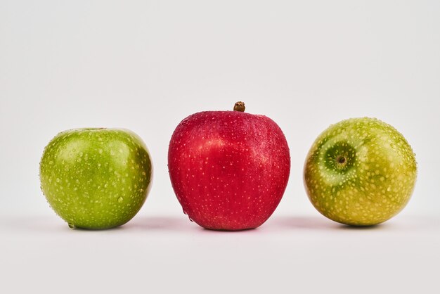 Manzanas verdes y rojas sobre superficie blanca.