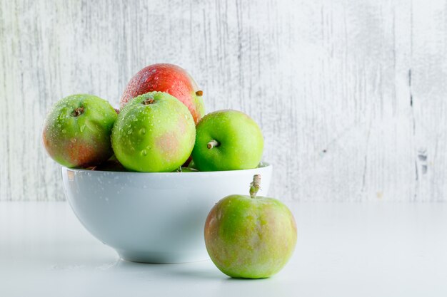 Manzanas en una vista lateral del tazón en blanco y sucio