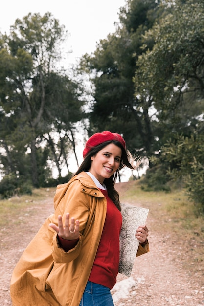 Mapa sonriente de la tenencia de la mujer joven en la mano que hace gesto de la llamada