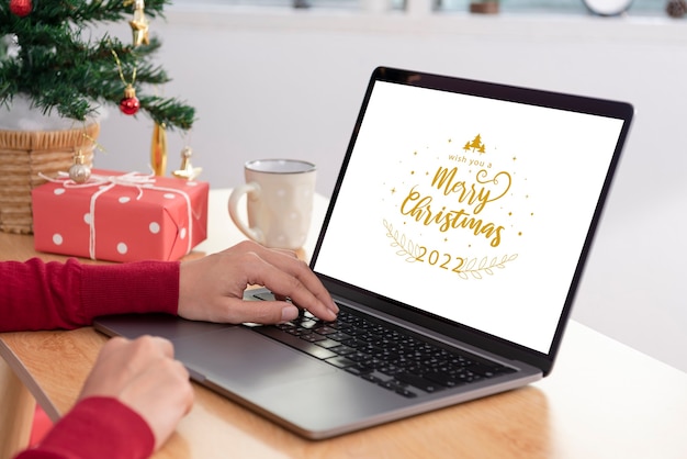 Maqueta de computadora portátil con pantalla blanca en la mesa de oficina en el día de Navidad