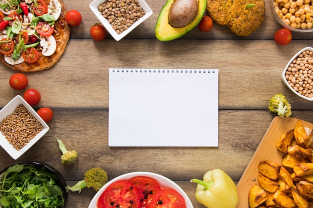 Maqueta de cuaderno rodeada de comida vegana
