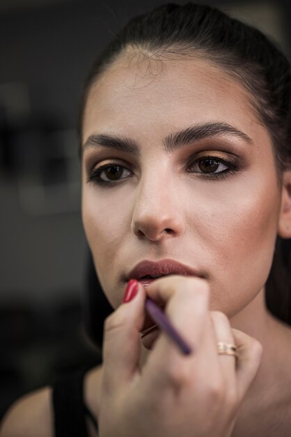 Maquilladora aplicando lápiz labial en modelo