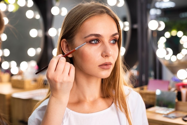 Maquilladora aplicando sombra de ojos en la cara