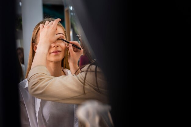 Maquilladora aplicando sombra de ojos con pincel en la cara