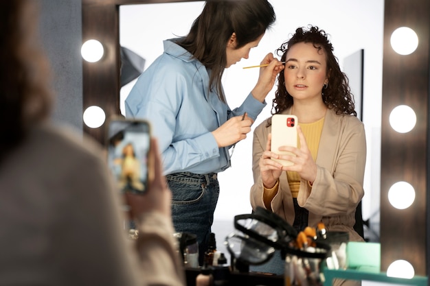 Foto gratuita maquilladora preparando modelo para sesión de fotos