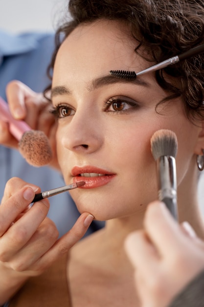 Foto gratuita maquilladora preparando modelo para sesión de fotos