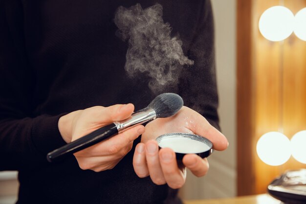 Maquilladora profesional que trabaja en el salón. El hombre de la profesion femenina. Concepto de igualdad de género. Manos masculinas con primer plano de cepillo