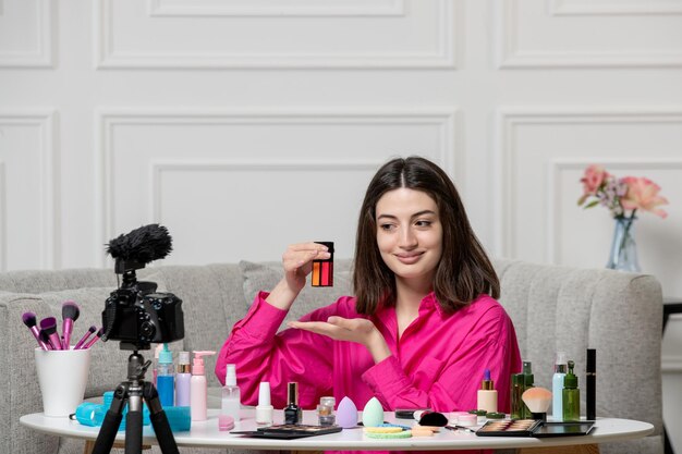 Maquillaje blogger linda encantadora hermosa joven grabando blog en cámara con lápices labiales