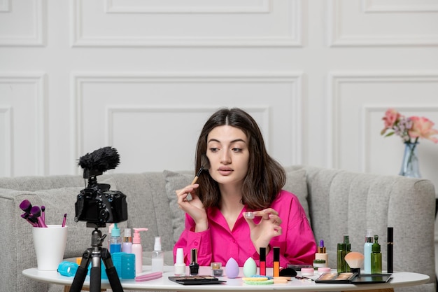 Maquillaje blogger linda encantadora hermosa joven grabando video en cámara con bronceador