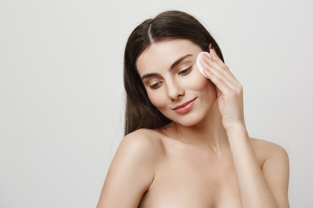 Maquillaje de despegue de mujer linda sonriente con algodón