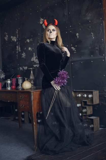 Maquillaje de Halloween hermosa mujer con peinado rubio. Chica modelo en traje negro. Tema de Halloween.