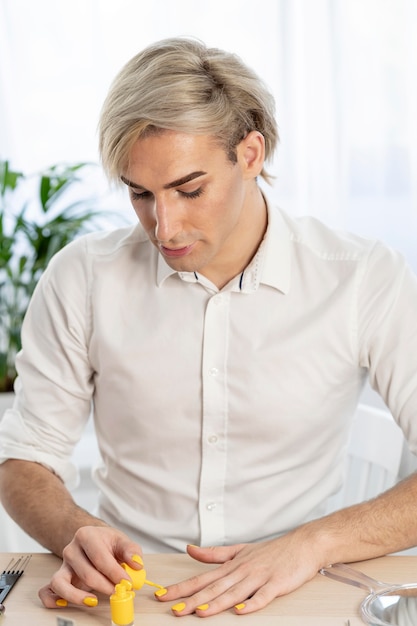 Maquillaje masculino pintando sus uñas