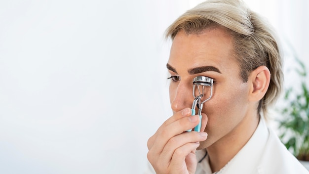 Foto gratuita maquillaje masculino con rizador de pestañas