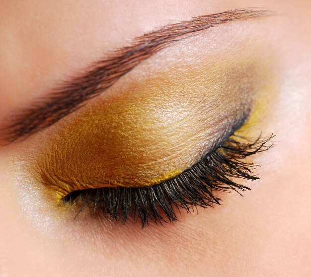 Maquillaje de moda: sombra de ojos de color amarillo brillante en los ojos cerrados